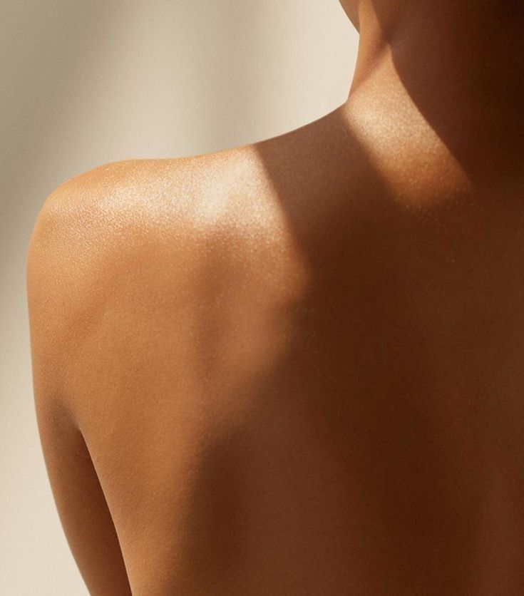 Back view of a woman’s bare shoulder glowing under natural sunlight, showcasing healthy, radiant skin – a visual from IMEAN Beauty post. How to know if your skin barrier is damaged.