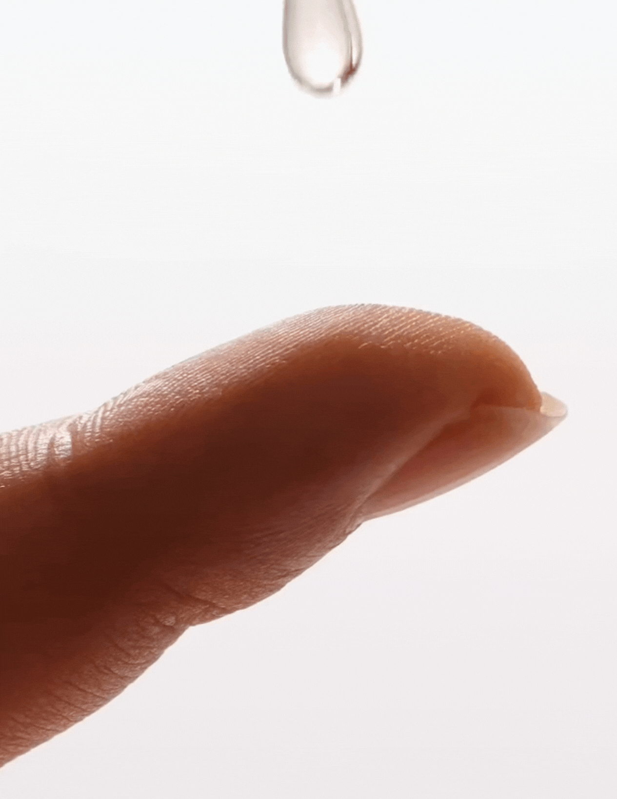 Slow-motion drop of peptide serum landing on fingertip, capturing the lightweight texture and precise application of IMEAN’s formula