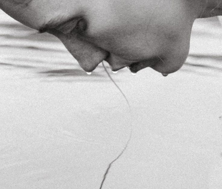 Person drinking water from a straw with reflection on water surface