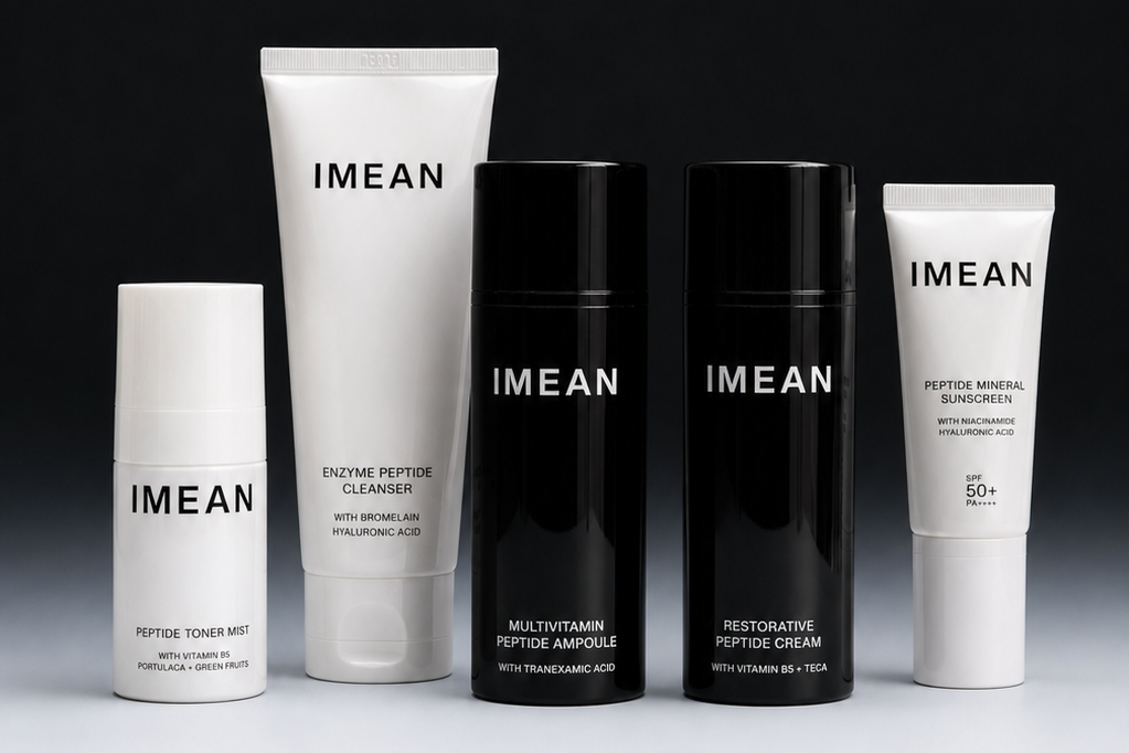 Five IMEAN skincare bottles and tubes arranged on a white surface against a dark gradient background. The set includes a white tube, a black gel bottle, a black cream bottle, and two white tubes.