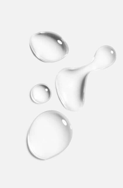 Clear skincare serum droplets on white background — representing consistent application and minimalist intentional skincare by IMEAN Beauty