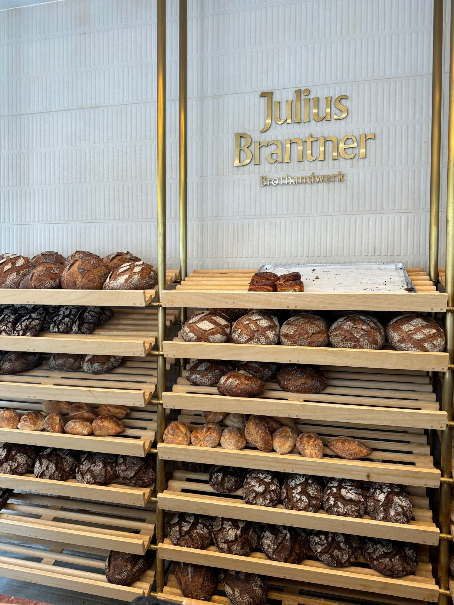 Loaves of freshly baked bread displayed in wooden shelves at Julius Brantner Brothandwerk bakery in Munich — a visual in Sarah’s Edit to Munich, Germany from IMEAN Beauty’s travel guide.