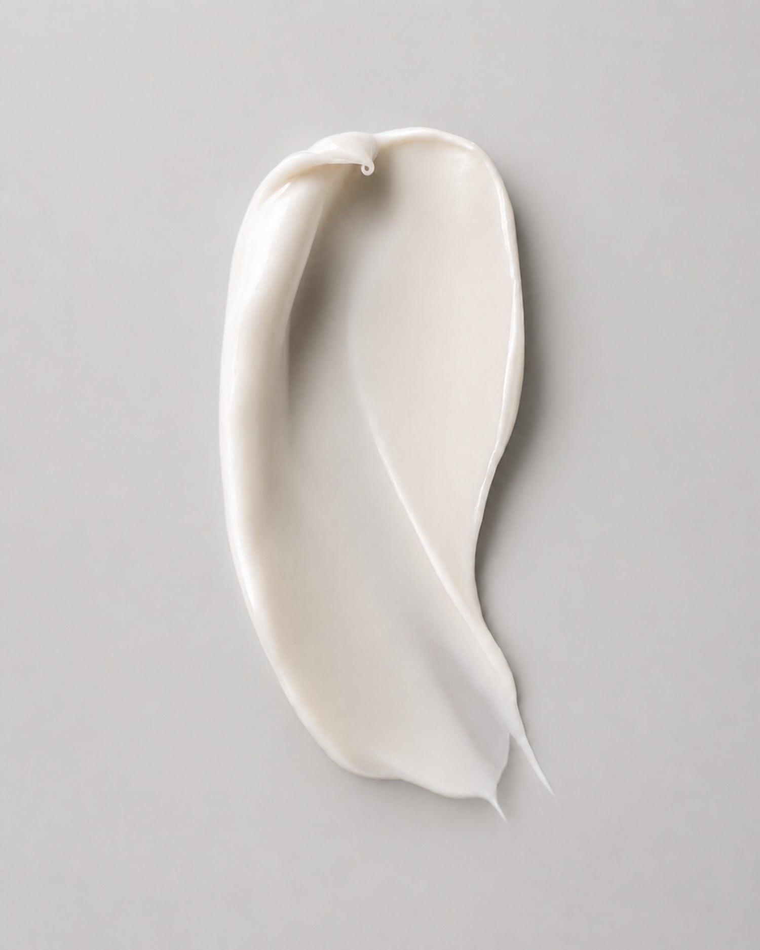 A swipe of rich, ivory IMEAN peptide cream on a soft grey background